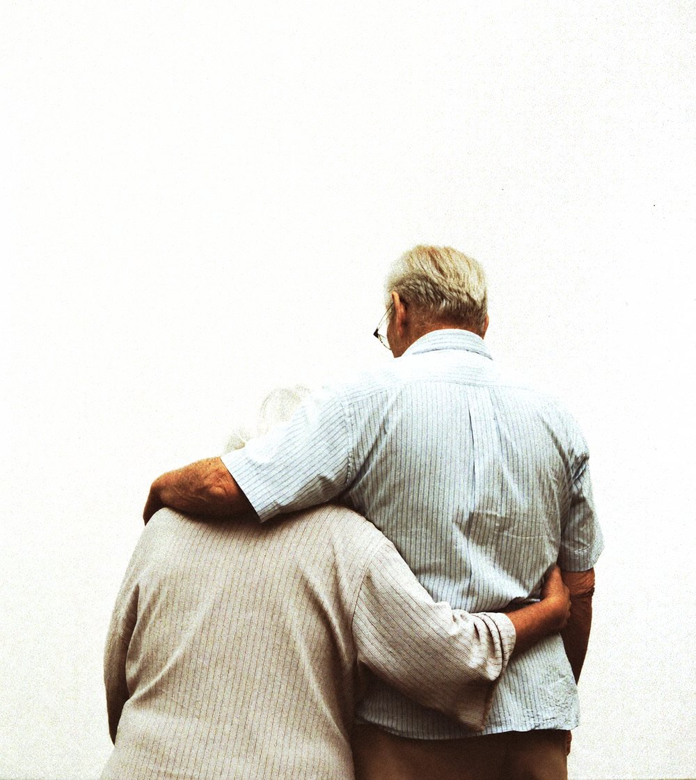 An older couple standing together, seen from behind